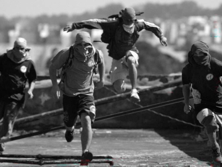 Vermummte Personen laufen in Richtung der Kamera