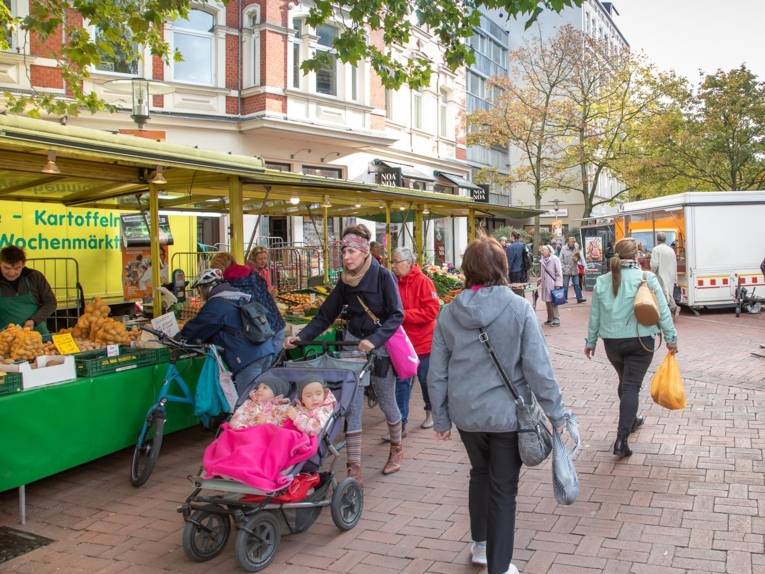 Menschen unterschiedlichen Alters (vom Kleinkind im Kinderwagen bis zur Seniorin) auf dem Wochenmarkt auf der Lister Meile.