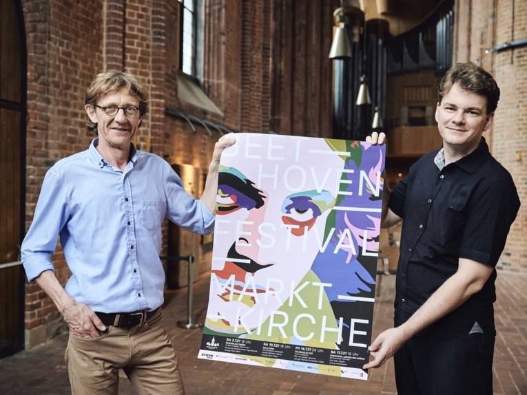 Zwei Männer halten ein Plakat.