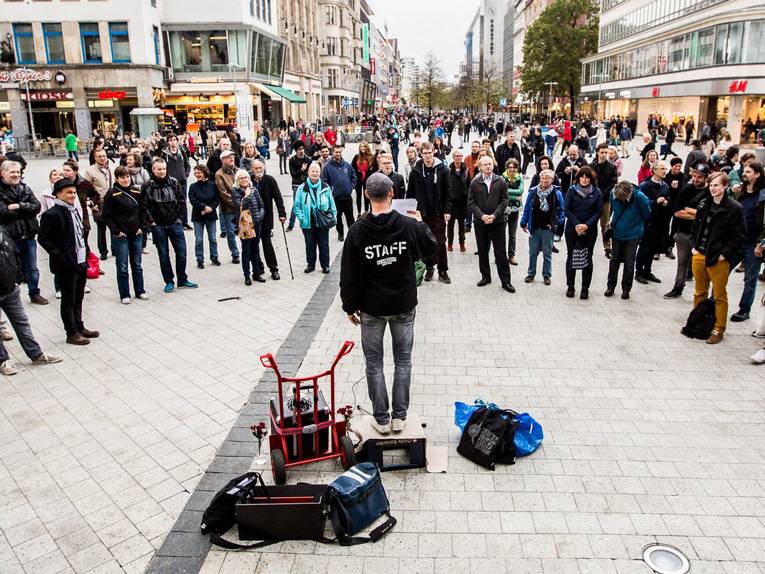 Ein Mann mit Mikrofon liest seinen Text vor einer Menschenmenge vor