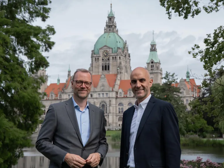 Zwei Männer im Park. In Hintergrund das Neue Rathaus von Hannover.