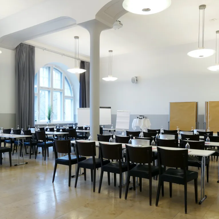 Untere Ebene eines Restaurants. Festlich gedeckte Tische mit goldenen Stühlen.