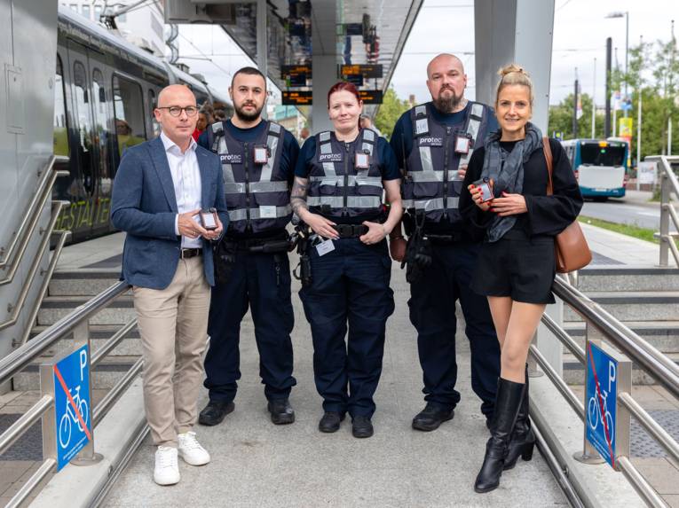 Fünf Personen stehen an einem Bahnsteig