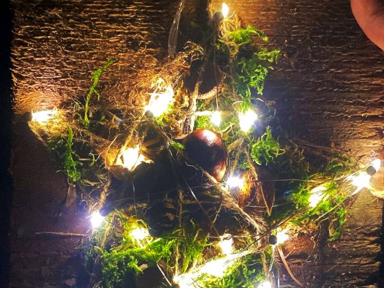 Ein gebastelter, leuchtender Stern liegt auf einem Tisch.