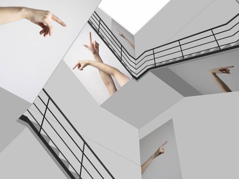 Treppenhaus, in dem Fotografien von zeigenden Armen und Fingern angebracht sind