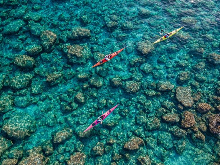 Kajakfahrer fahren über grün schimmerndes Wasser vor Kreta