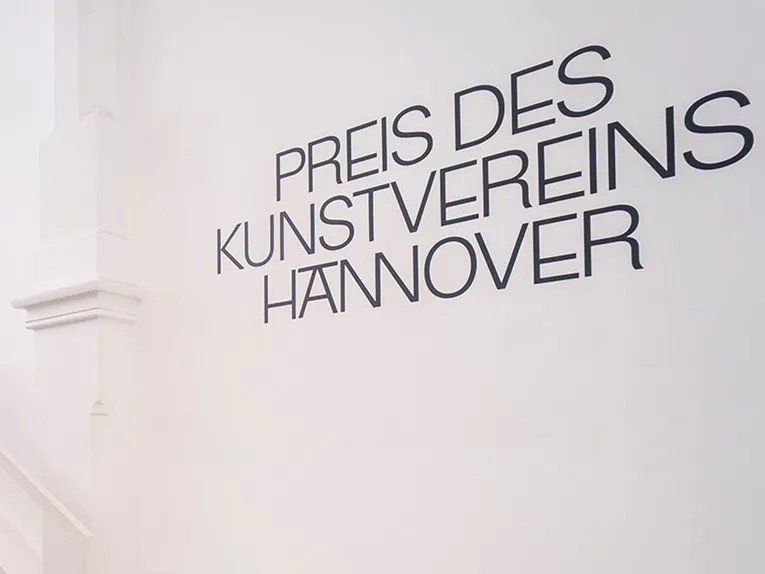 Das Foto zeigt eine weiße Wand in den Räumlichkeiten des Kunstvereins Hannover, auf der der Schriftzug „Preis des Kunstvereins Hannover“ steht.