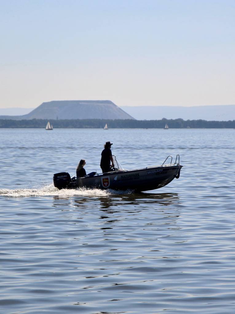 Zwei Personen fahren mit einem kleinen Motorboot über das Steinhuder Meer.