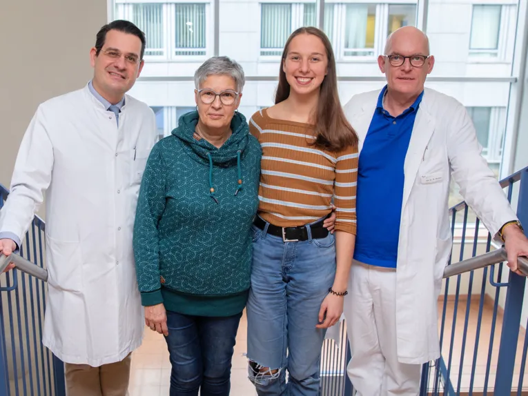 Zwei Frauen und wei Männer in weißen Kitteln stehen auf einer Treppe.
