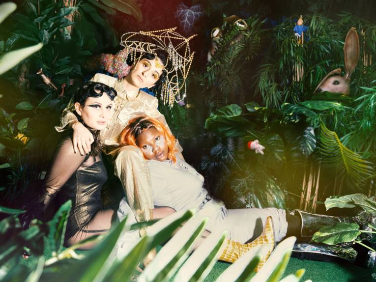 Drei Frauen vor einer Dschungelkulisse.