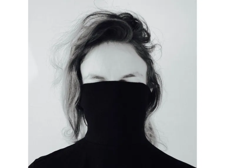 Eine Person in einem Pulli, der bis über die Augen über das Gesicht gezogen ist.