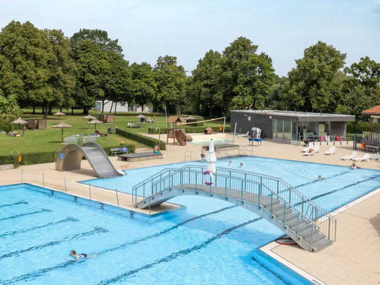 Au&szlig;enschwimmbecken mit Br&uuml;cke zwischen Schwimmer- und Nichtschwimmerbereich und Rutsche im Nichtschwimmerbereich