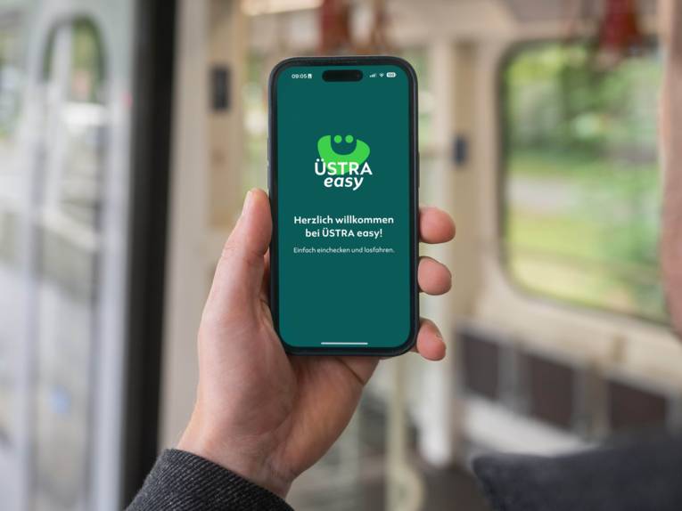 Eine Hand hält ein Smartphone in der Hand und hat die App namens Üstra easy auf dem Display angezeigt