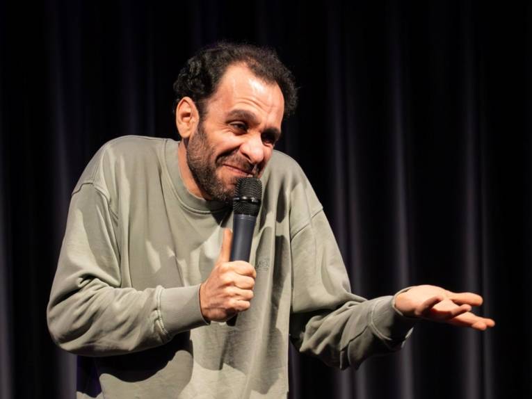 Zu sehen ist ein Comedian auf der Bühne.