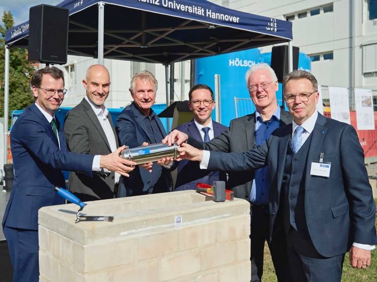 Fünf Männer legen einen symbolischen Grundstein
