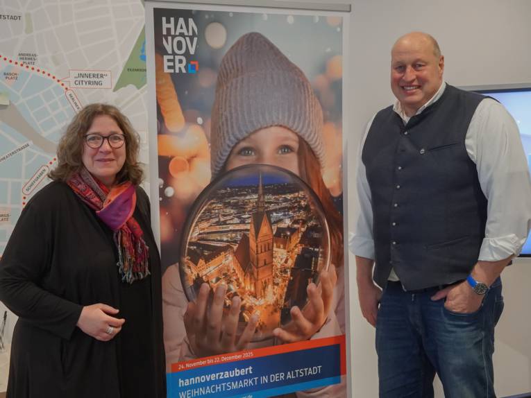 Zwei Personen neben einem Aufsteller.