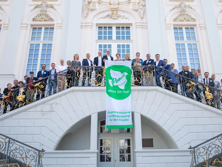 Zahlreiche Menschen auf einer Treppe. In der Mitte ein Banner der Mayors for Peace.