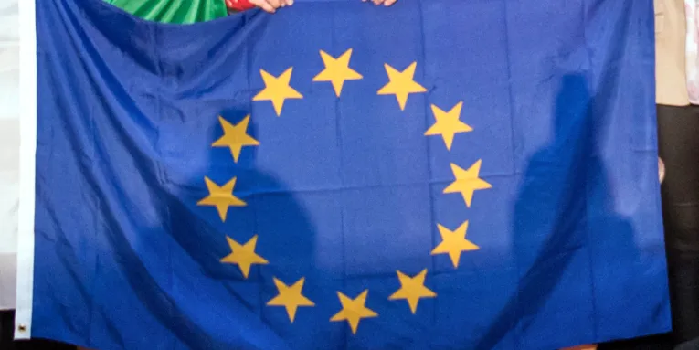 Kinder halten bei einer Sportveranstaltung die Flagge der EU.