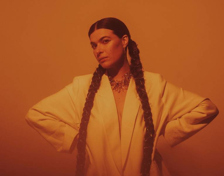 Frau mit sehr langen geflochtenen Zöpfen stützt die Hände in die Hüften.