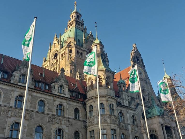 Vier Mayors for Peace-Flaggen wehen vor dem Neuen Rathaus in Hannover im Wind.