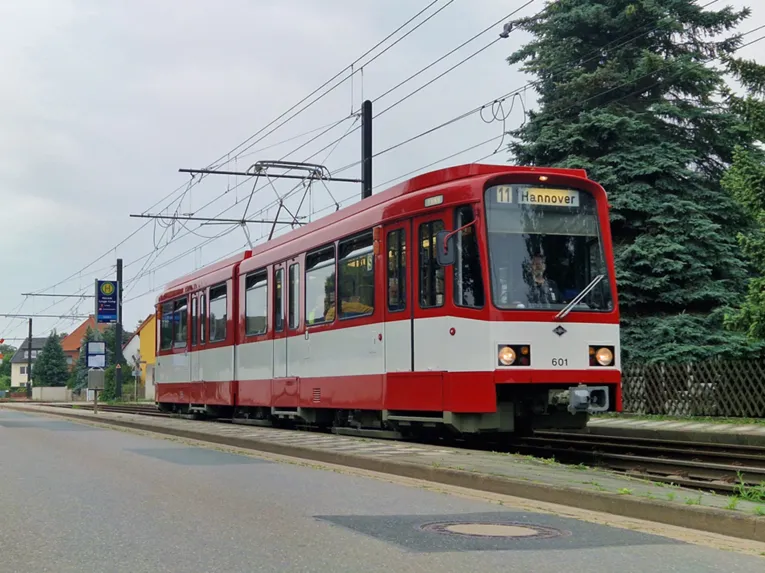 Ein rot lackierter Straßenbahnwagon an einer Haltestelle