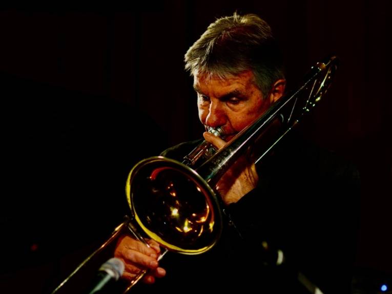 Ein Mann bläst in seine Trompete.