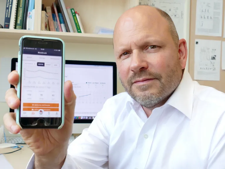 Mann hält Smartphone in die Kamera