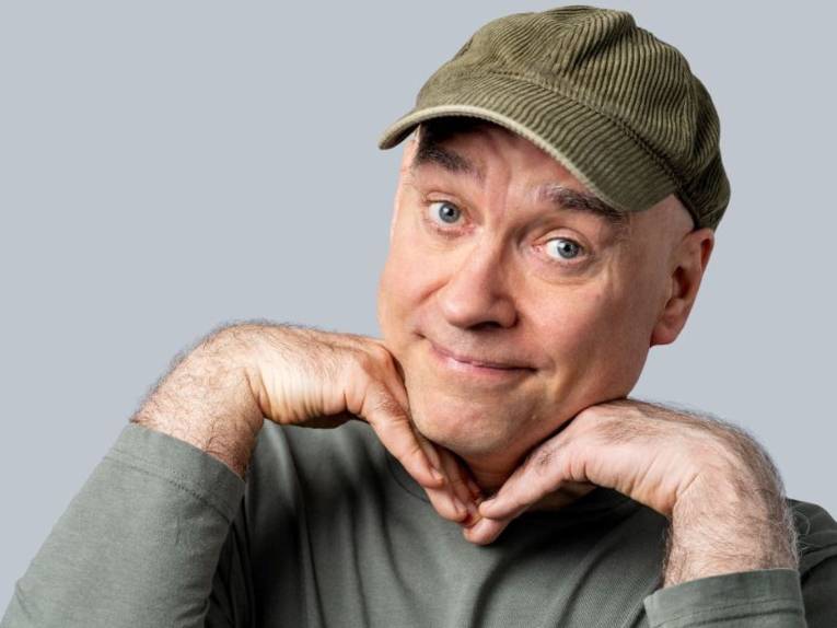 Mann mit Cordkäppi stützt das Kinn auf die Hände