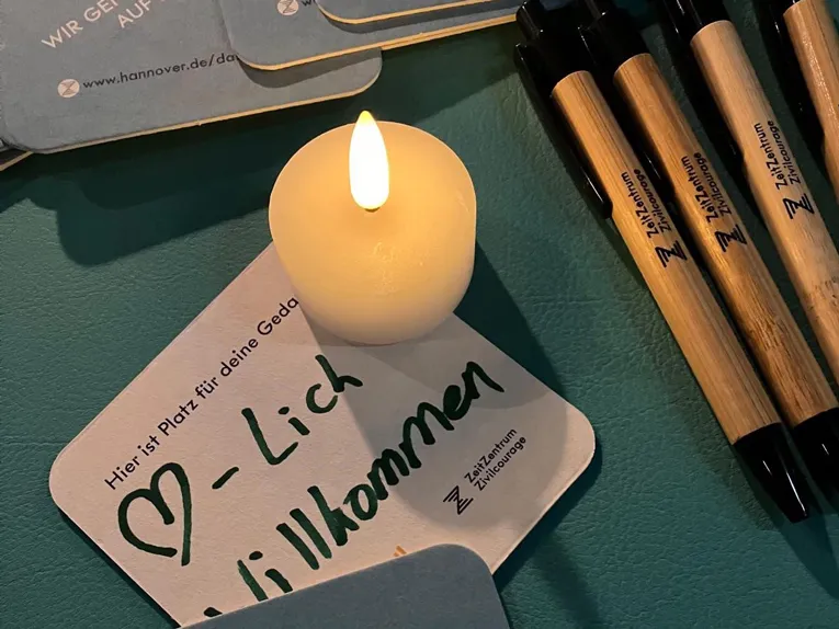 Ein Bierdeckel neben Stiften und einer Kerze