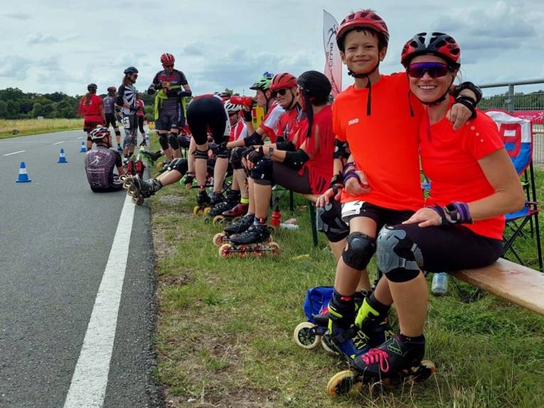 Inline-Skater sitzen auf Holzbänken an einem Straßenrand.