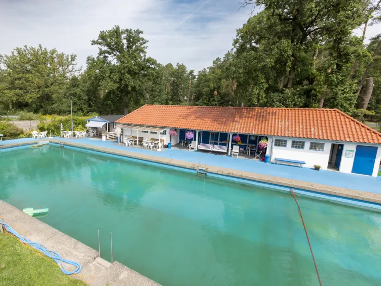 Schwimmbecken, im Hintergrund ein Geb&auml;ude und diverse Sitzm&ouml;glichkeiten