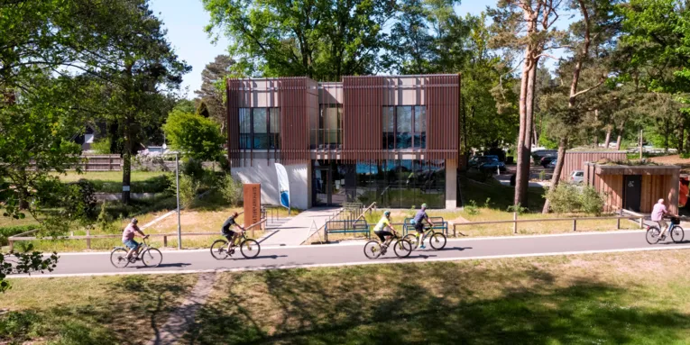 Radfahrerinnen und Radfahrer fahren auf dem Steinhuder Meer Rundweg und kommen direkt am Naturpark-Haus in Mardorf vorbei.