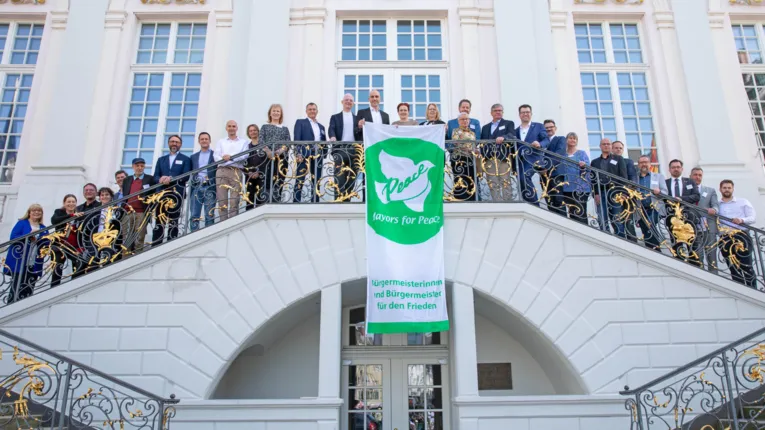 Zahlreiche Menschen auf einer Treppe. In der Mitte ein Banner der Mayors for Peace.