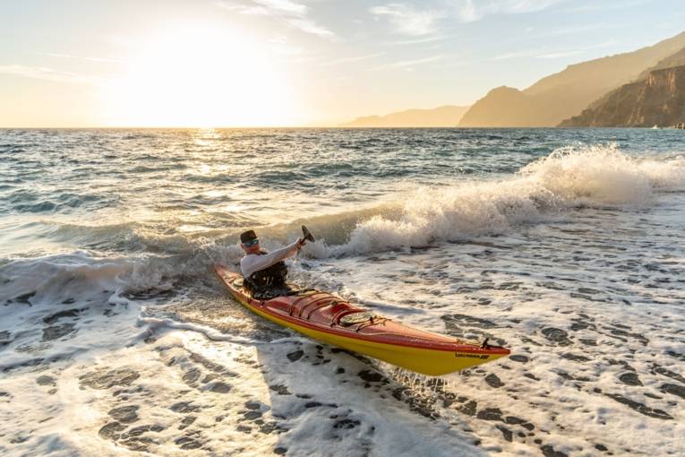 Ein Kajakfahrer surft auf einer Welle im Meer