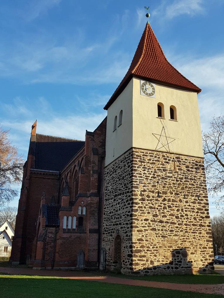 Neugotisches Kirchengebäude mit einem Kirchturm mit rotem Ziegeldach.