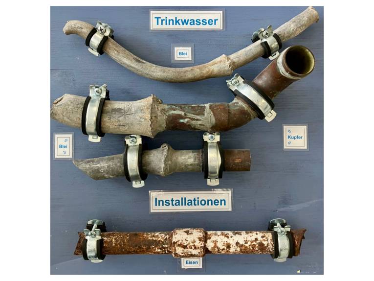 Diverse Rohrabschnitte mit Bleirohren auf einer Schautafel