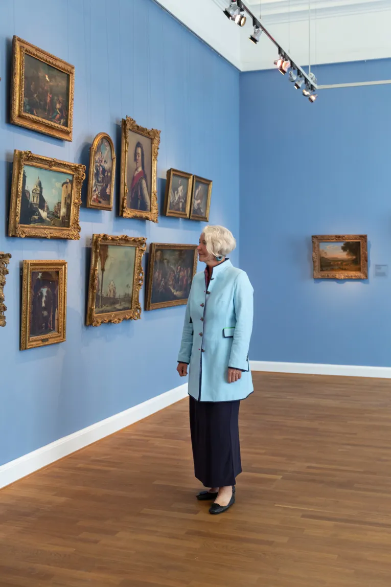Eine &auml;ltere Frau betrachtet neugierig barocke Kunstgem&auml;lde im Museum
