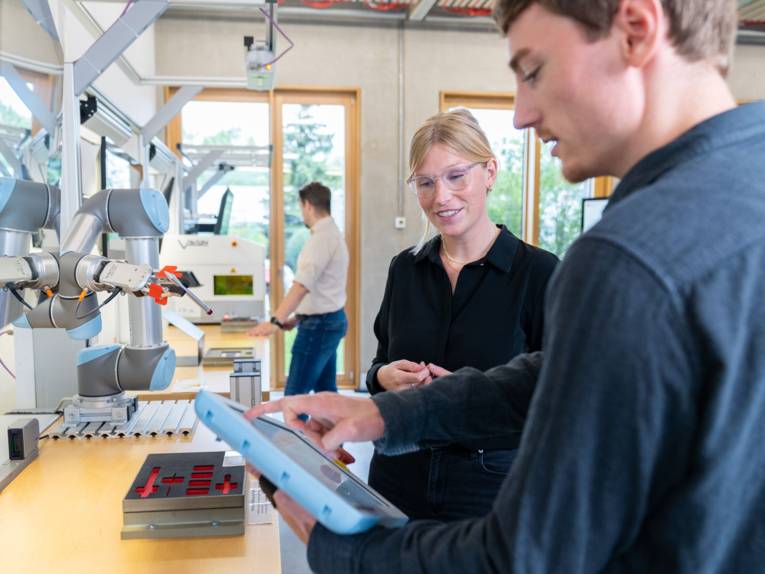 Eine Frau und ein Mann mit Industrieroboter in einem Labor.