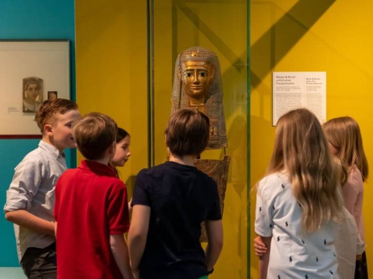 Kinder vor der Maske einer Frauenmumie in der Dauerausstellung