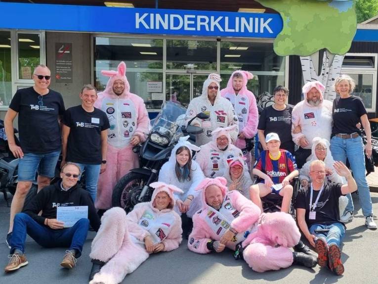 Menschen posieren vor der Kamera, einige tragen rosa Hasenkostüme.
