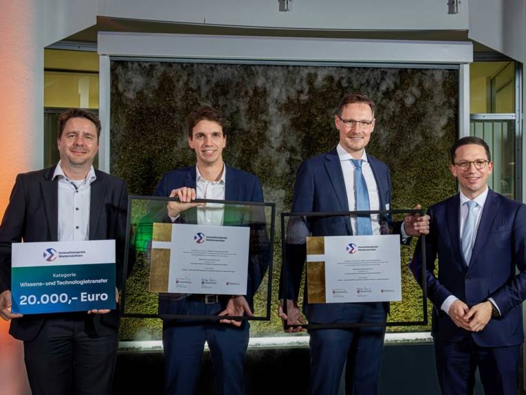 Vier Männer, drei halten Urkunden in den Händen.