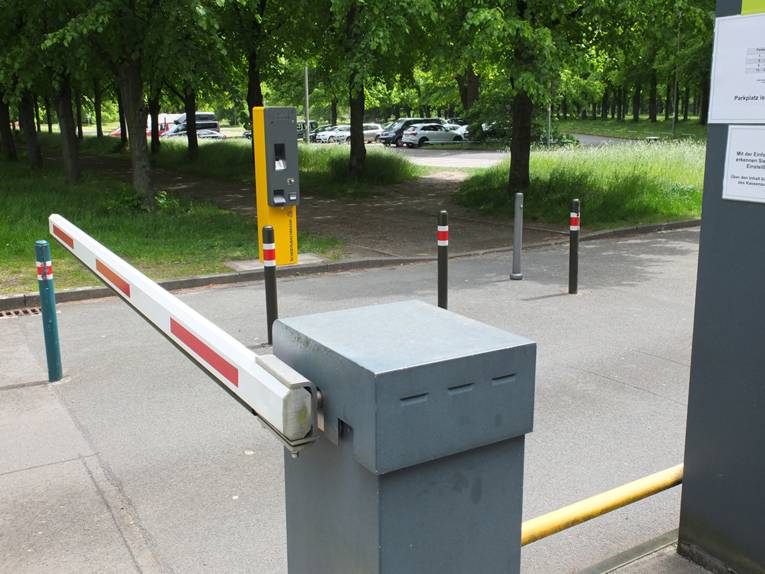 Kartenautomat und geschlossene rotweiße Schranke am Parkplatz