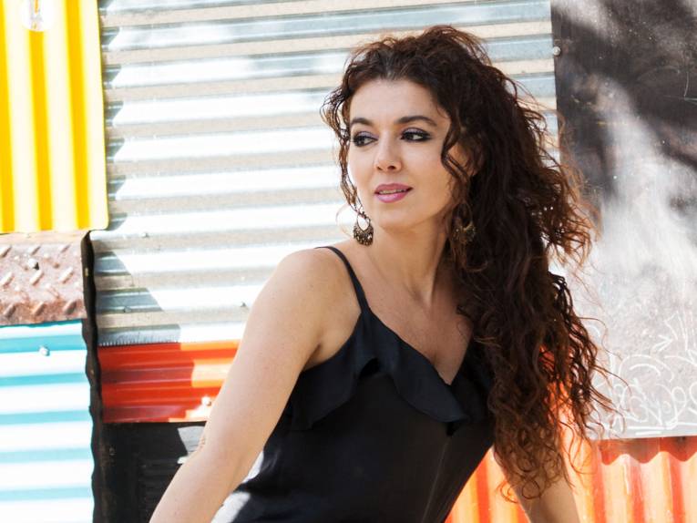 Lächelnde Frau mit sehr langen Locken in einem Trägertop