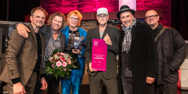 Die sechs Musiker der Band stehen auf der Bühne mit dem Stadtkulturpreis in den Händen.