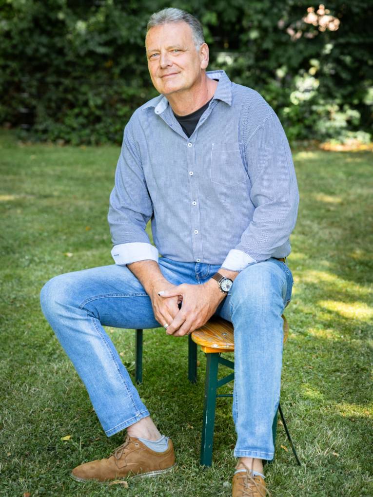 Ein Mann sitzt unter freiem Himmel auf einer Bank.