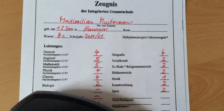 Zeugnis mit schlechten Noten, auf dem ein Telefonhörer liegt.