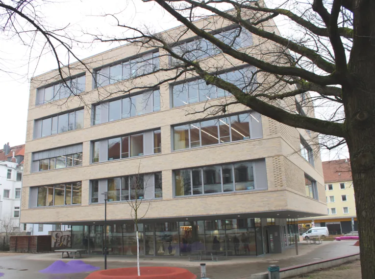 Ein helles Geb&auml;ude, unten eine Fensterfront, dar&uuml;ber vier weitere Etagen.