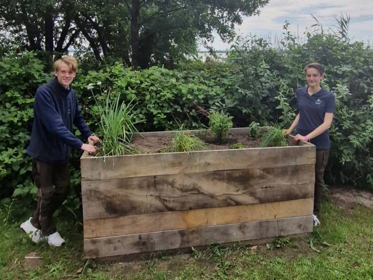Zwei junge Menschen an einem Hochbeet