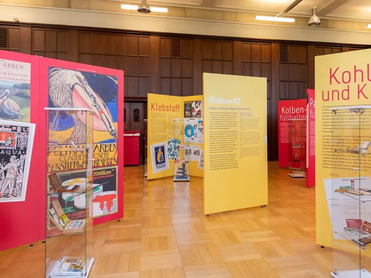 Blick in Ausstellung zur Unternehmensgeschichte der Marke Pelikan mit gelben und roten Infotafeln