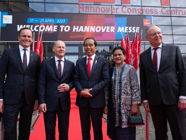 Vier Männer und eine Frau bei der Eröffnung einer Messe.